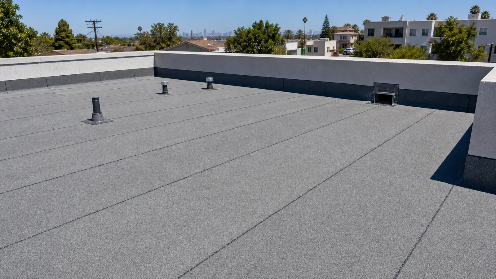 Gray modified-bitumen low-slope roof with membrane laps, parapet flashing and scupper