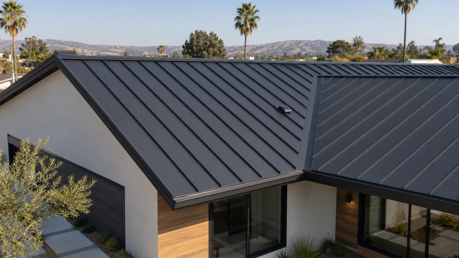Matte charcoal standing-seam metal roof with clean ridge, valley and eave trim