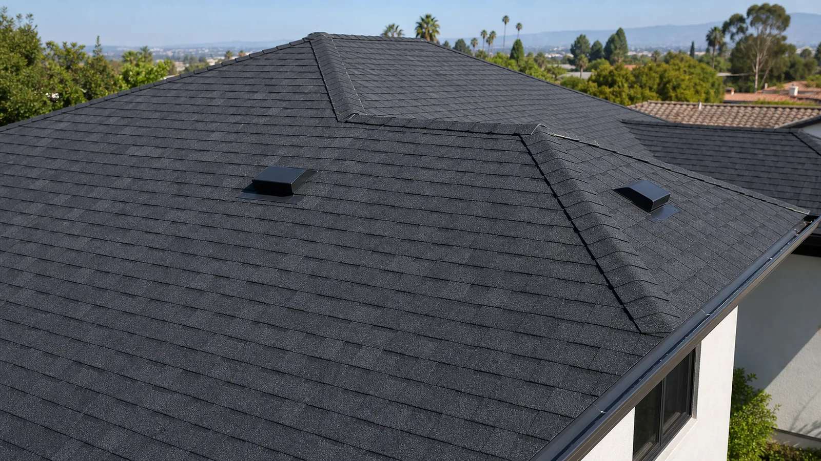 Finished charcoal architectural shingle roof with ridge caps, vents and clean roof edges