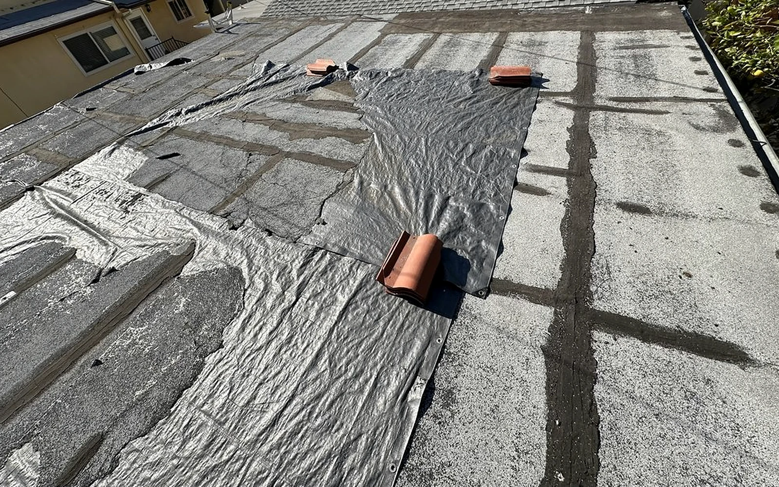 Weathered and patched low-slope roof damage documented after rain and wind exposure