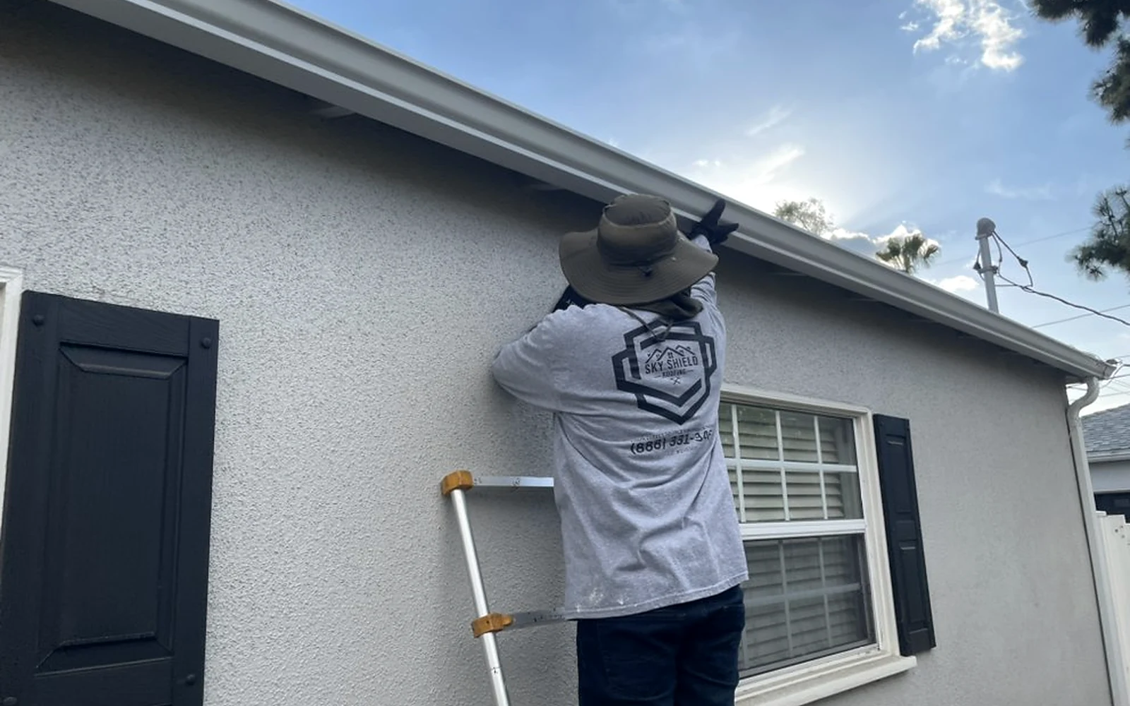 Sky Shield Roofing technician installing a seamless aluminum gutter on a Toluca home